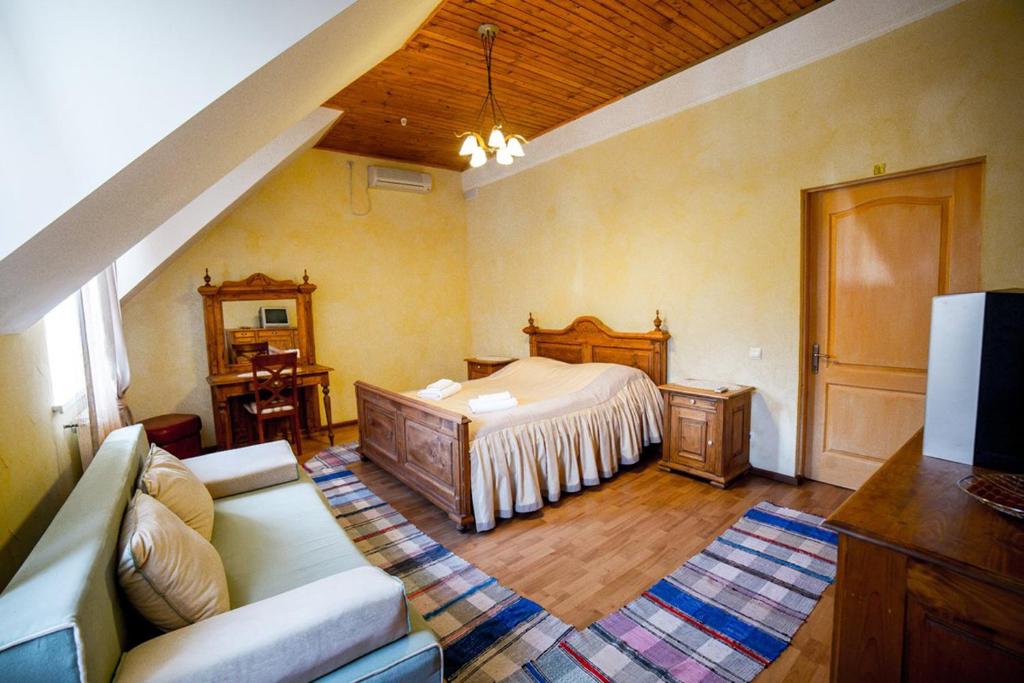 ein Schlafzimmer mit einem Bett und einem Sofa in einem Zimmer in der Unterkunft Готель Мараморош in Shayan