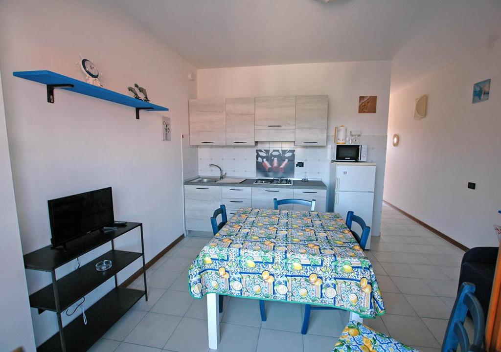 una camera con tavolo e una cucina con tavolo e sedie di LE MAREE EMATITE a Porto Azzurro