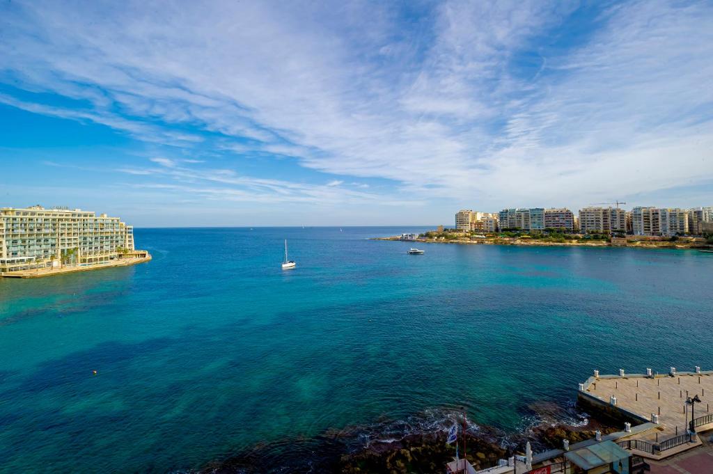 einen Blick auf einen großen Wasserkörper mit Gebäuden in der Unterkunft Spinola Bay top floor seafront 3 bedroom Apartment with panoramic sea views - by Getawaysmalta in St Julian's