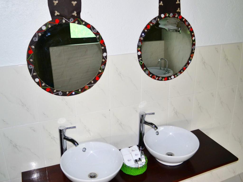 ein Badezimmer mit zwei Waschbecken und zwei Spiegeln in der Unterkunft Osero Lodge in Ololaimutiek