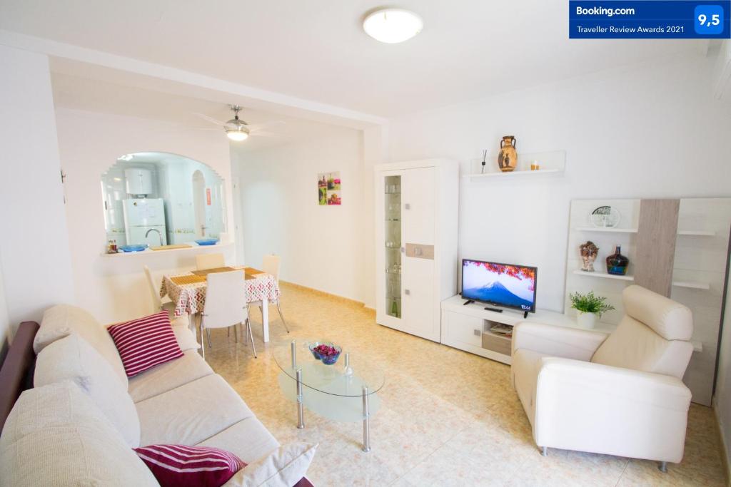 uma sala de estar com um sofá branco e uma televisão em Alacant Home: Santa Pola. Piso moderno a 200 metros de la playa em Santa Pola