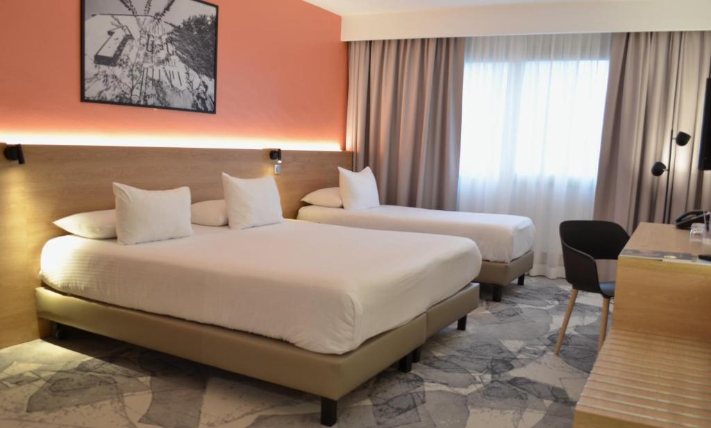 a hotel room with two beds and a desk at Hotel des Congrès in Villeurbanne