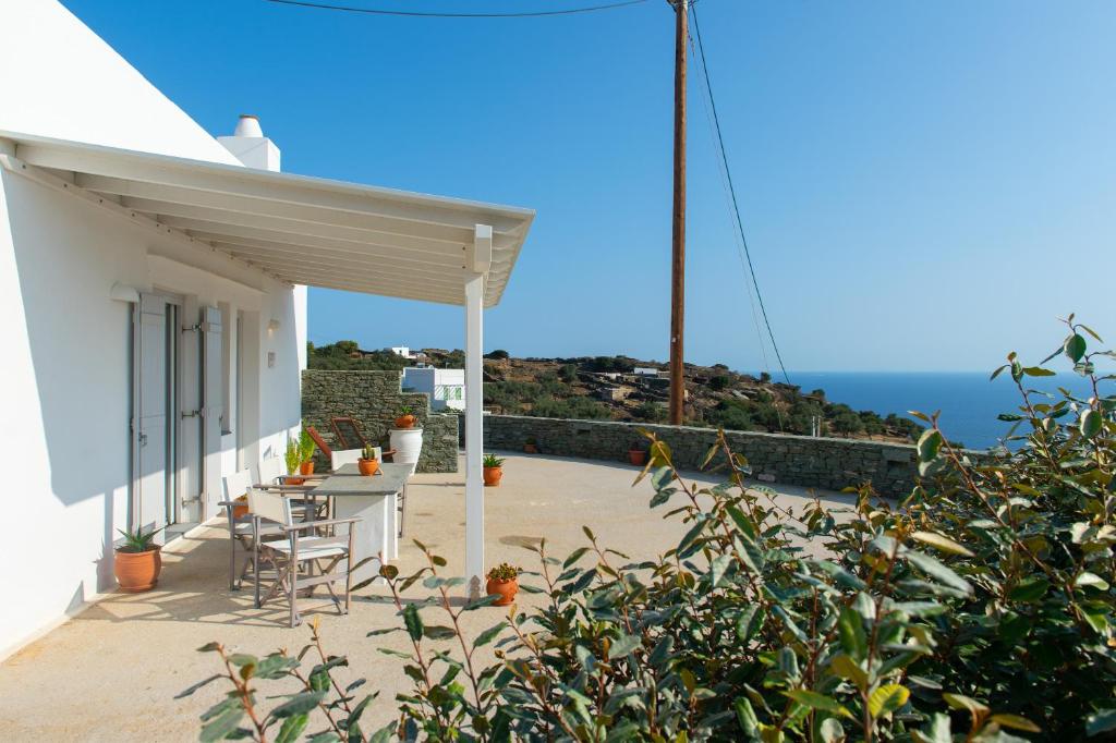 een patio met een tafel en stoelen en de oceaan bij Grey House in Exámbela