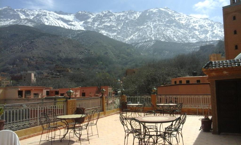 uma varanda com mesas e cadeiras e montanhas cobertas de neve em Hôtel Restaurant Les Etoiles Du Toubkal em Imlil
