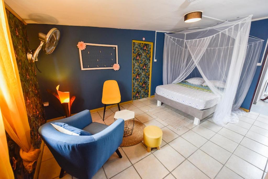 Habitación con 1 dormitorio con 1 cama y 1 silla en La Maison des Oeillets Aéroport Roland Garros, en Sainte-Marie