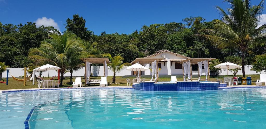 una gran piscina con sillas y sombrillas en Condomínio RCR Green Field Casas para Temporada, en Arraial d'Ajuda
