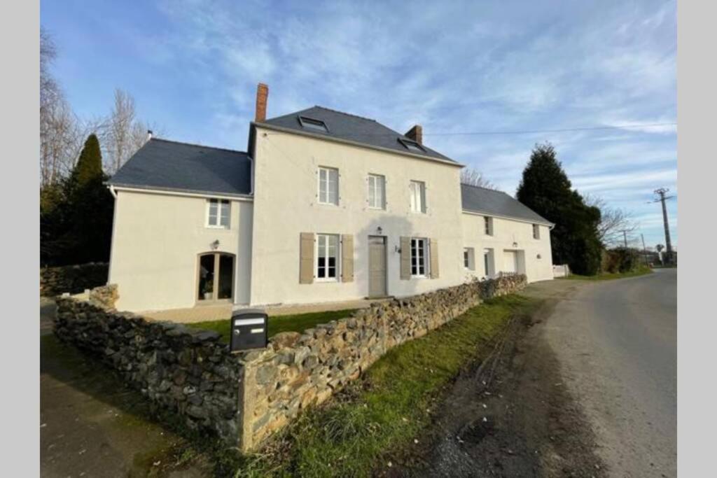 uma casa branca com uma parede de pedra ao lado de uma estrada em Studio indépendant 2 pers - Châtillon sur Colmont la petite gare em Châtillon-sur-Colmont