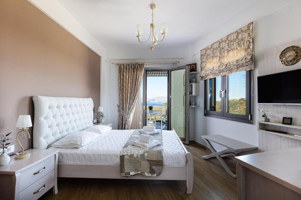 a bedroom with a white bed and a large window at Villa Chryssi in Kissamos