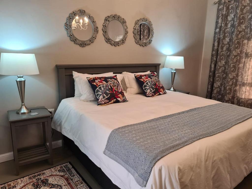 馬加利斯堡的住宿－Steenkoppies semi self catering apartment，一间卧室配有一张带两盏灯和两面镜子的床。