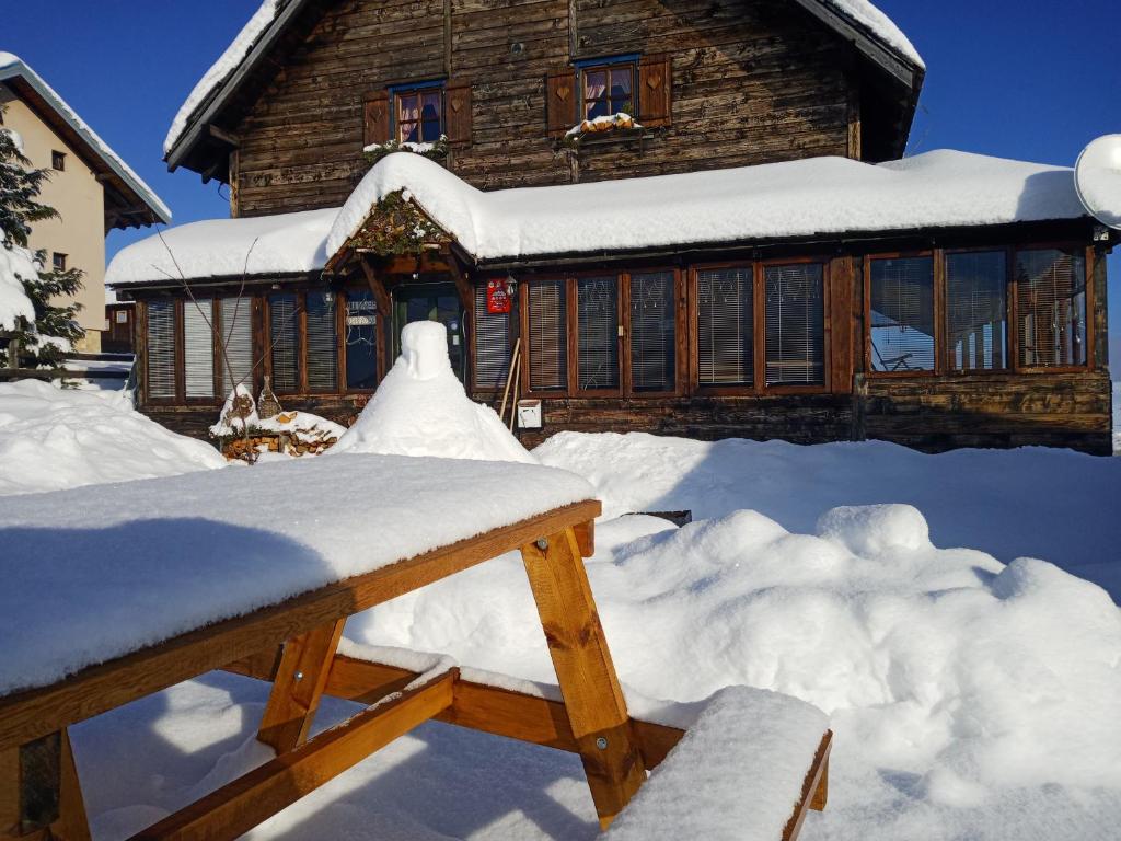 a house covered in snow in front at Planinarski dom "Tornik" Zlatibor in Ribnica