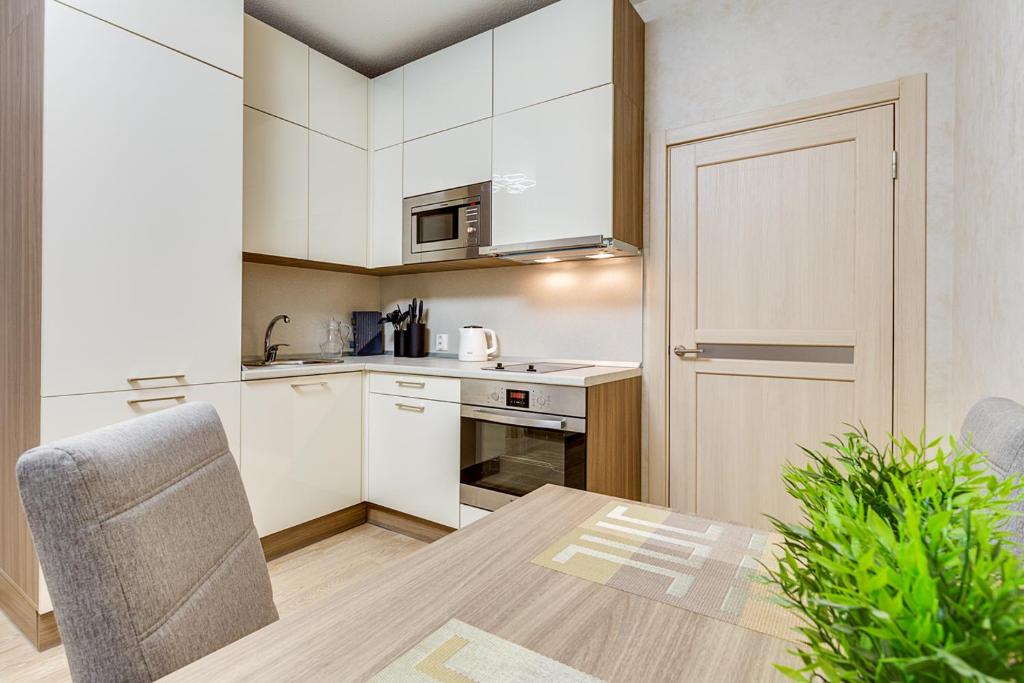 una cocina con armarios blancos y una mesa con una silla en Apart 21 (Salut-11 Group), en San Petersburgo