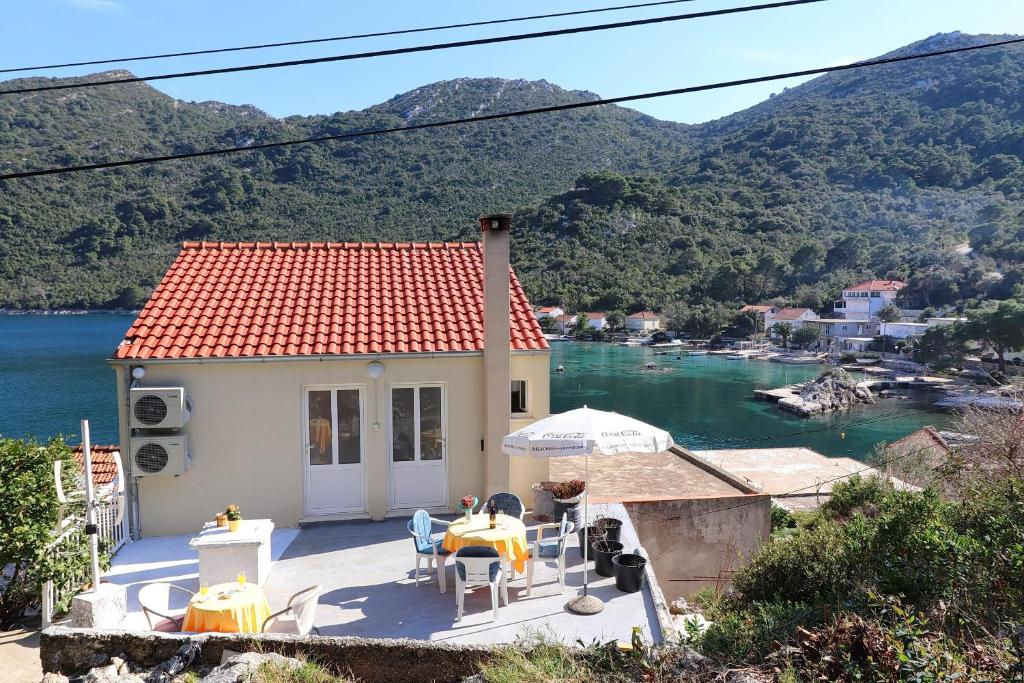 Cette petite maison dispose d'une terrasse avec une table et des chaises. dans l'établissement Apartments Belin Mljet, à Okuklje