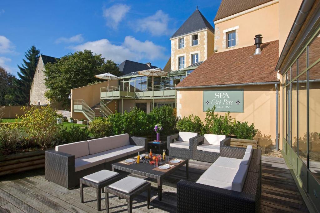 eine Terrasse mit Sofas, einem Tisch und Stühlen in der Unterkunft Coté Parc in Rémalard