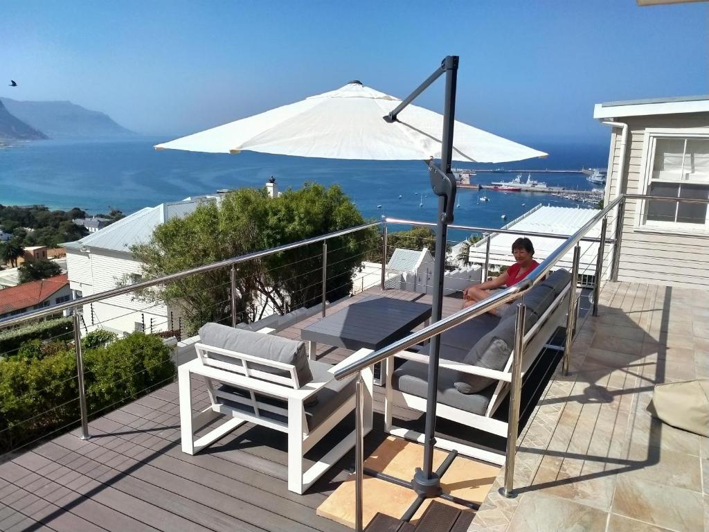 eine Person, die mit einem Regenschirm auf einem Deck sitzt in der Unterkunft Admiral's Waterfall Self-Catering in Simonʼs Town