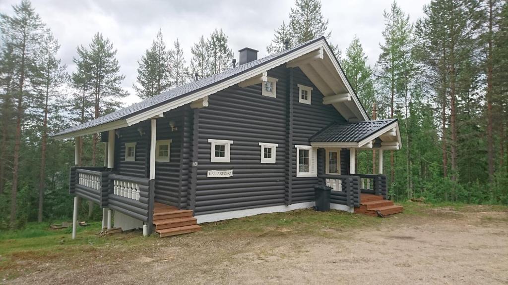 a black cabin in the middle of the woods at Hallanpoika mökki in Hyrynsalmi