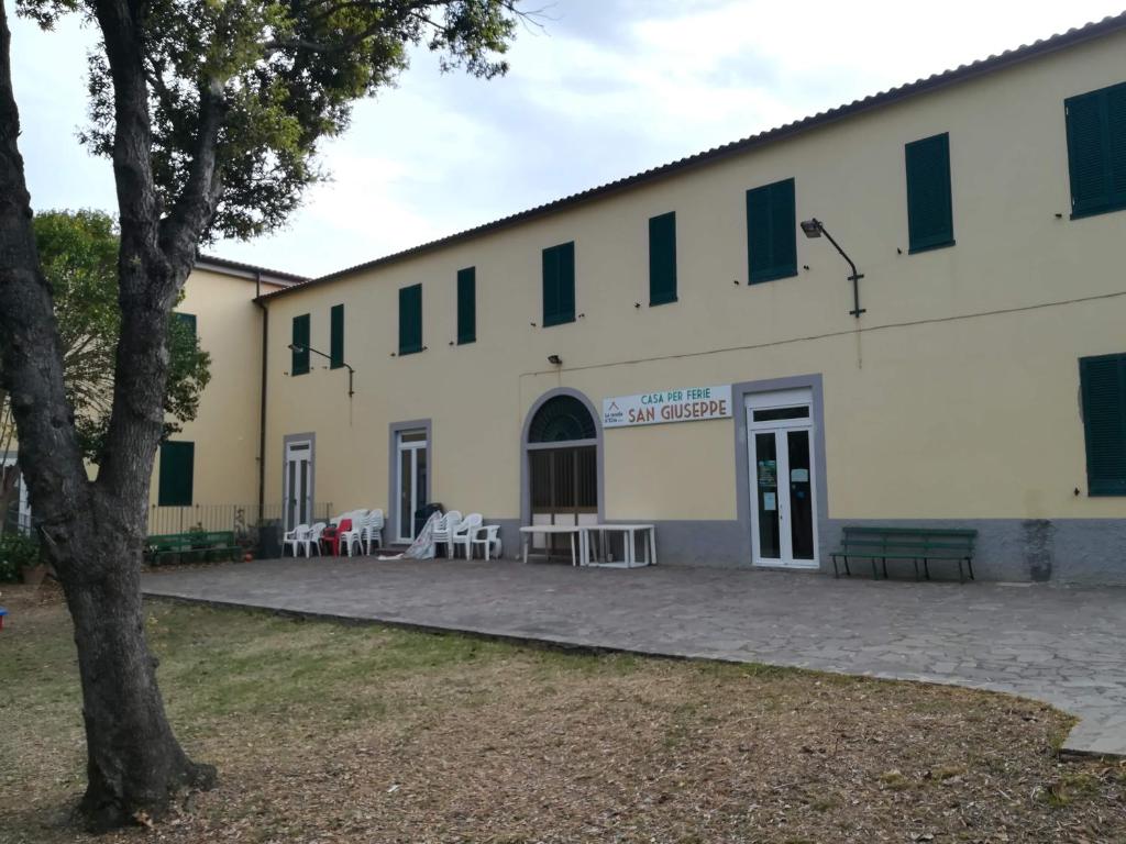 un bâtiment avec des tables et des chaises à l'extérieur dans l'établissement Casa San Giuseppe - Isola d'Elba, à Cavo