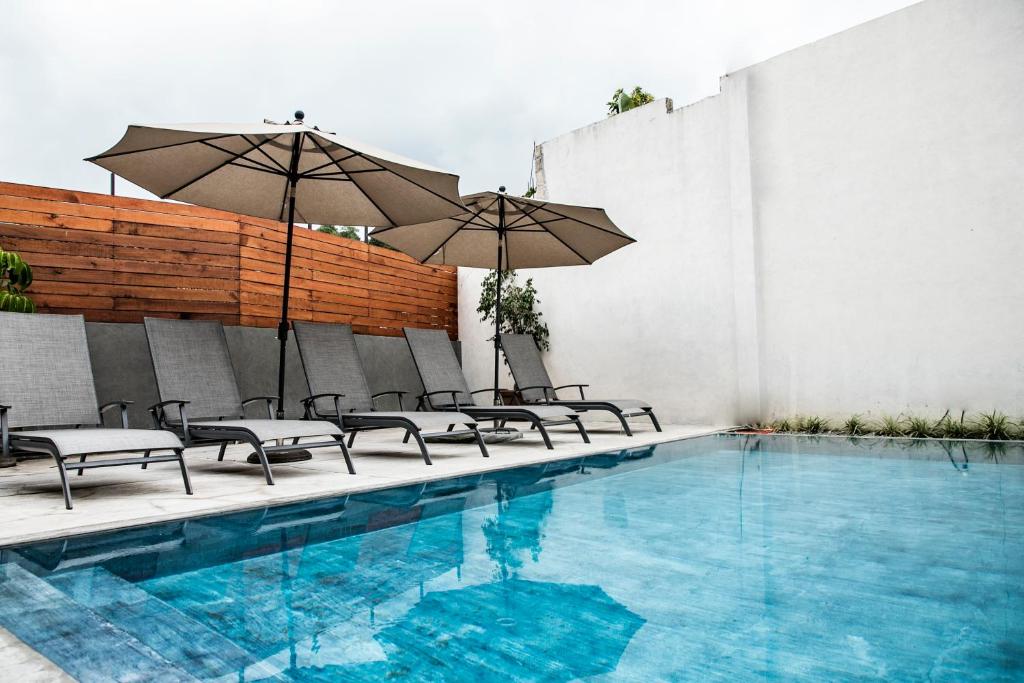 a pool with chairs and umbrellas next to a building at Villa Maria Hotel in Valle de Bravo