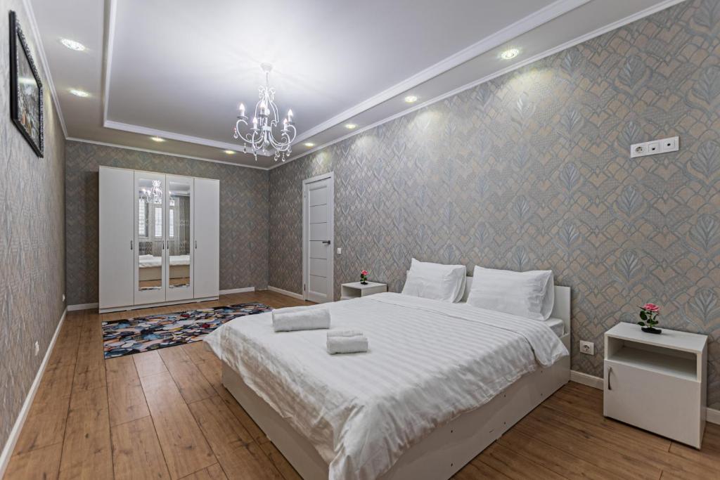 a bedroom with a large white bed and a chandelier at Happy House in Taldykolʼ