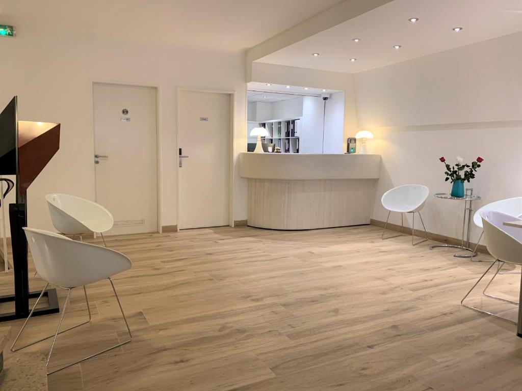 a room with white chairs and a counter and a kitchen at Hotel Francais in Luxembourg