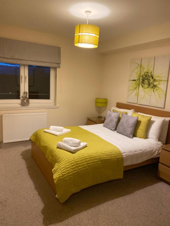 um quarto com uma cama grande e um cobertor amarelo em AB11 Apartments - Portland Street em Aberdeen