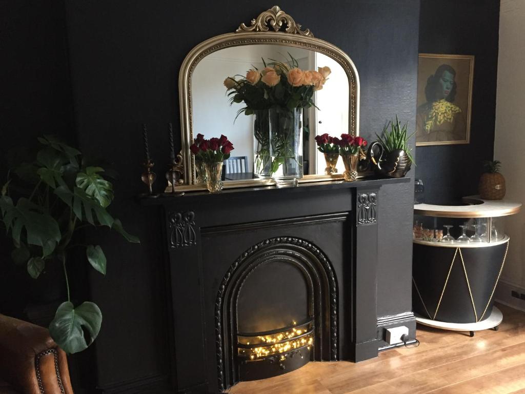 a black fireplace with a mirror and flowers on it at High Tor Guest House in Whitby