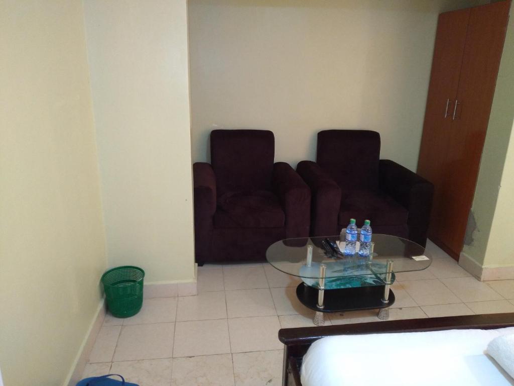 a living room with two chairs and a glass table at Crown Hotel Kericho in Kericho
