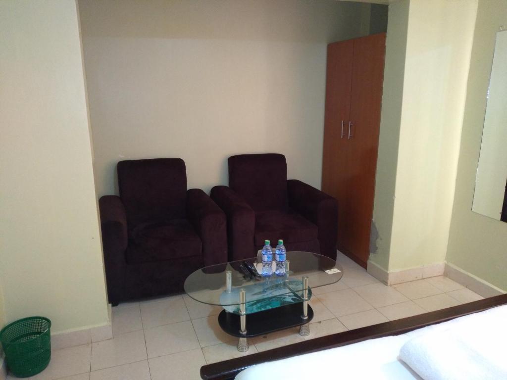 a living room with two chairs and a glass table at Crown Hotel Kericho in Kericho