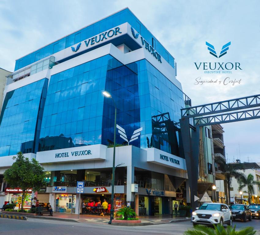 un edificio de cristal con un coche aparcado delante de él en Hotel Veuxor, en Machala