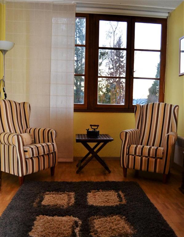 two chairs and a table in a room with windows at Apartamento con piscina en Enveitg in Enveitg