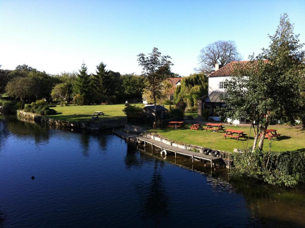 a river with tables and benches next to a building at Bridge Hotel Brandon in Brandon