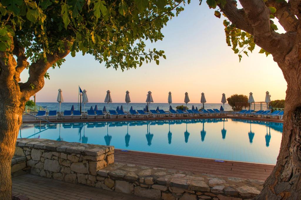 een zwembad met stoelen en de oceaan op de achtergrond bij Silva Beach Hotel in Chersonissos