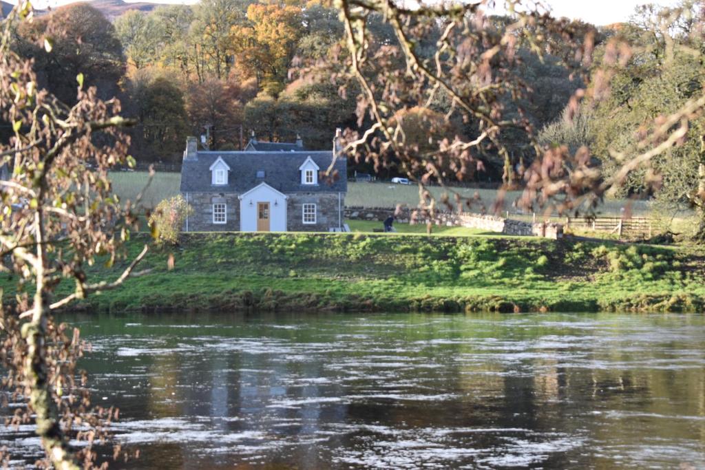uma casa numa ilha no meio de um rio em Heron Cottage, Port o Tay em Pitlochry