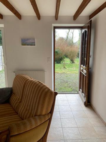 a living room with a couch and an open door at les landes in Plouër-sur-Rance