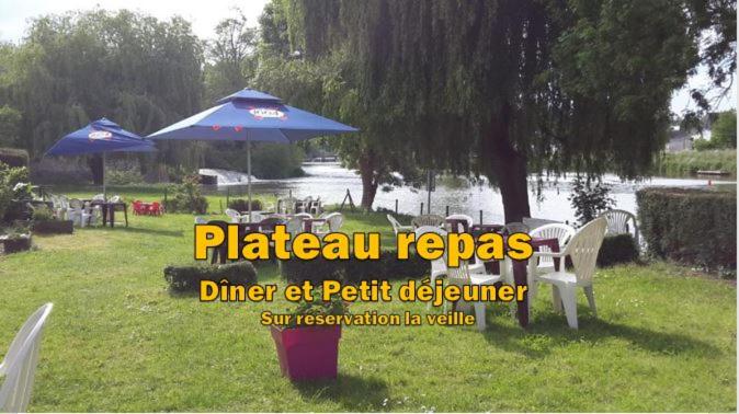 a park with tables and chairs and an umbrella at Grand Hotel in Le Pont Réan