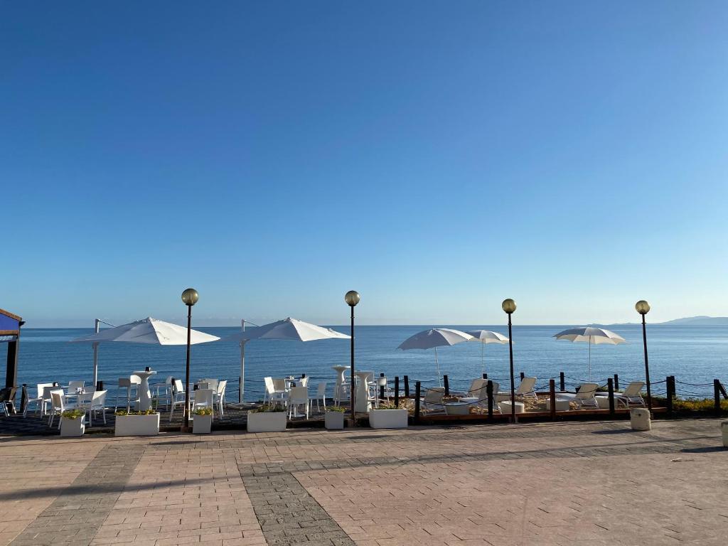 una fila di sedie e ombrelloni in spiaggia di La Locanda del Mare a Valledoria