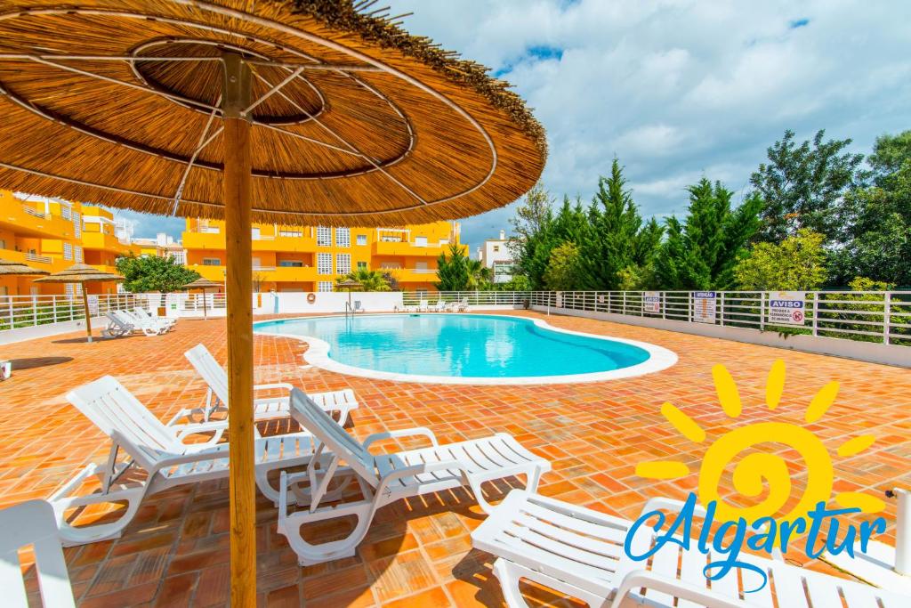 uma piscina com cadeiras e um guarda-sol em Royal Cabanas Golf by Algartur em Cabanas de Tavira