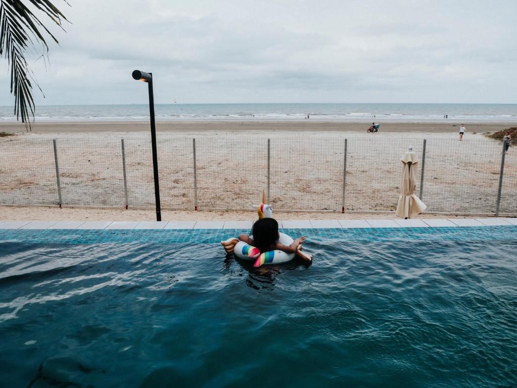 une personne assise dans l'eau à côté de la plage dans l'établissement Timur bay groundfloor pool & seaview, à Kuantan