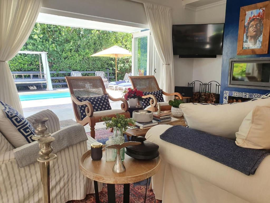 uma sala de estar com um sofá, cadeiras e uma mesa em Long Story Guest House em Plettenberg Bay