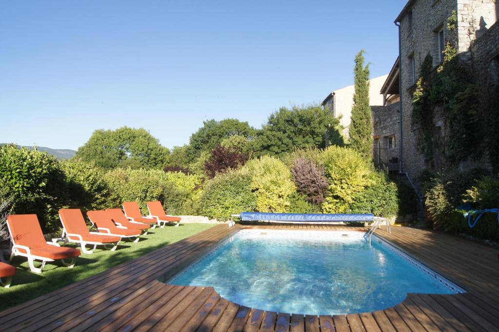 een zwembad met stoelen en een houten terras bij La Clavelière in Saint-Auban-sur-lʼOuvèze