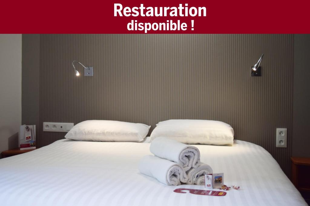 ein Bett mit weißer Bettwäsche und Handtüchern darauf in der Unterkunft Brit Hotel Reims La Pompelle in Reims
