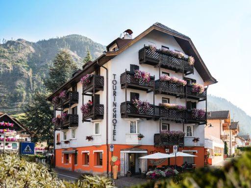 a building with flowers on the balconies of it at Hotel Touring in Predazzo