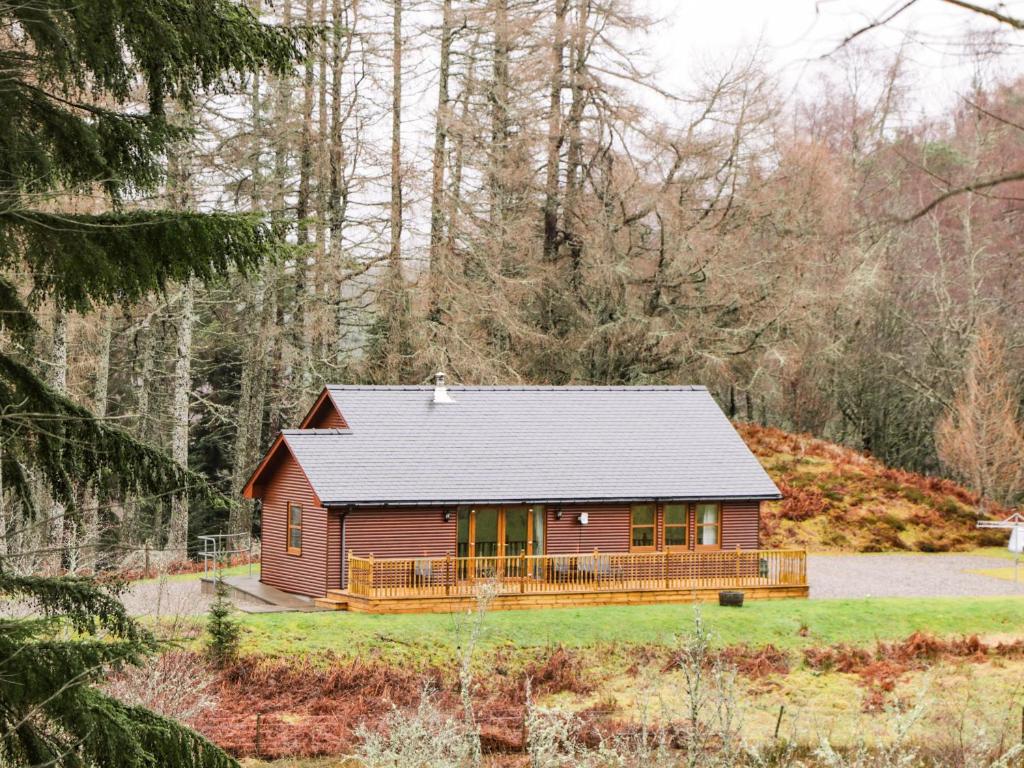 une maison rouge au milieu d'une forêt dans l'établissement Fersit Log Cottage, à Roybridge