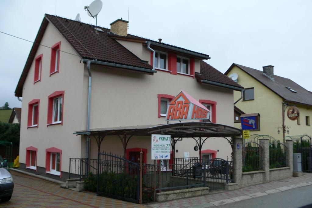 a white building with red windows and aeat inn at Penzion Abahouse in Liptovský Mikuláš