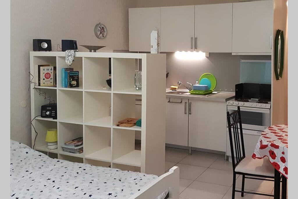 a kitchen with white cabinets and a table and a bed at Appt 2 étoiles agréable et calme vue sur montagnes in Amélie-les-Bains-Palalda