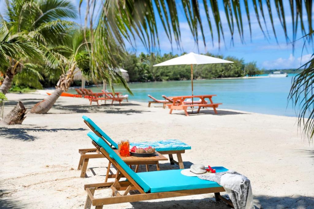 a picnic table and chairs on a beach at Tai Roto Bay in Arutanga