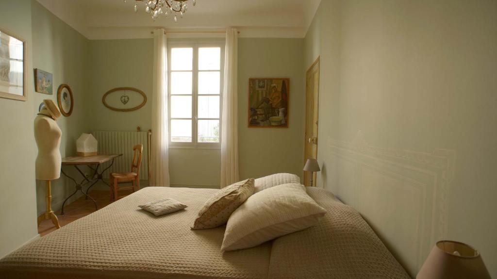 um quarto com uma cama com almofadas e uma janela em Au coin de la Roquette em Arles