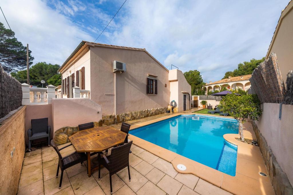 een zwembad met een houten tafel en stoelen naast een huis bij Casa Manolo in Cala Ratjada