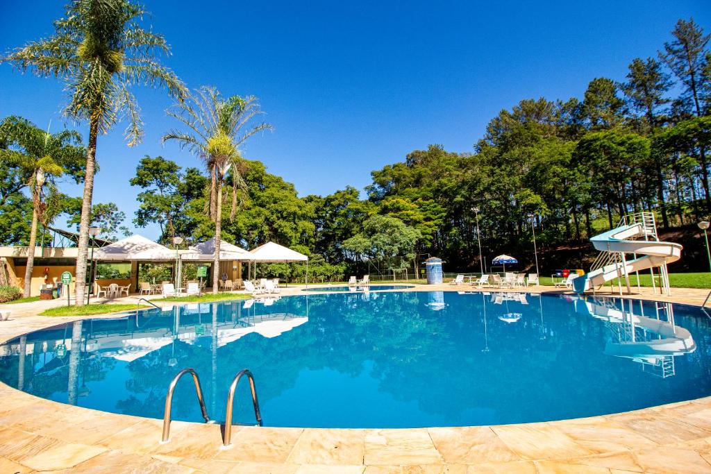 a swimming pool with blue water and palm trees at Hotel Nacional Inn Araxá Previdência in Araxá