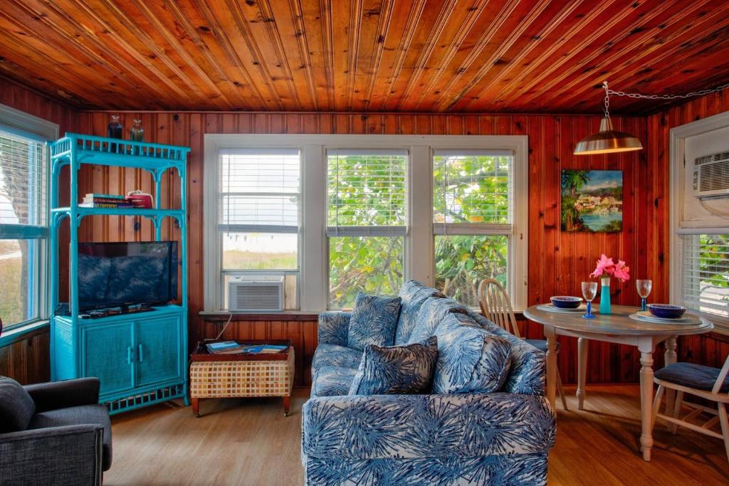 - un salon avec un canapé bleu et une table dans l'établissement 5 - Seahorse Cottages, à St. Pete Beach