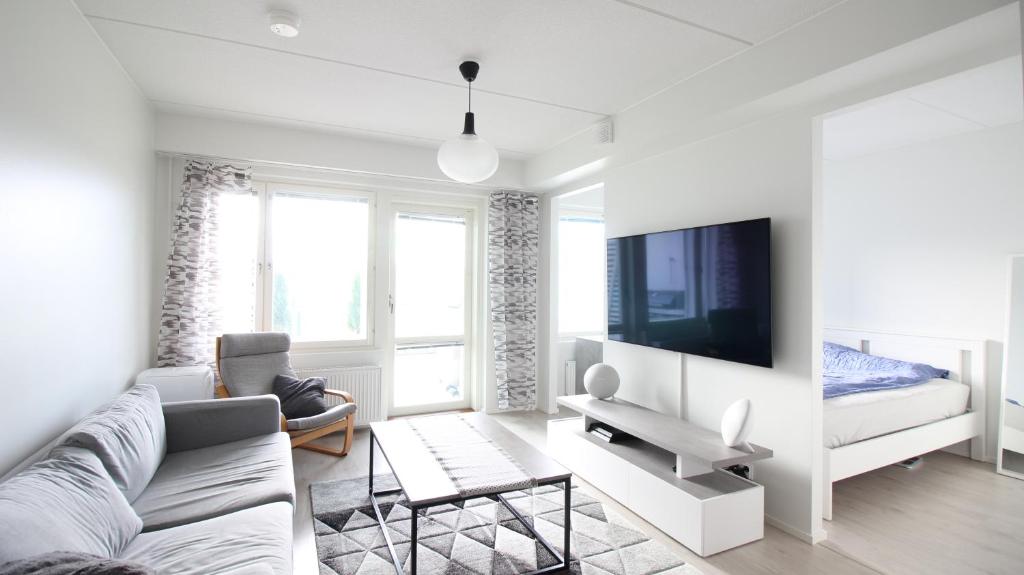 a white living room with a couch and a tv at New one bedroom apartment with TERRACE and Parking in Vantaa